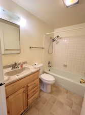 Full bathroom with toilet, tile patterned Linoleum floors, tiled shower / bath combo, and vanity