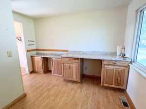 Kitchen with light counters, light LVP wood-type flooring, and plenty of natural light