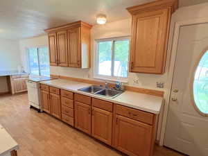 Kitchen featuring white portable dishwasher, light LVP / wood-style flooring, sink, and a textured ceiling