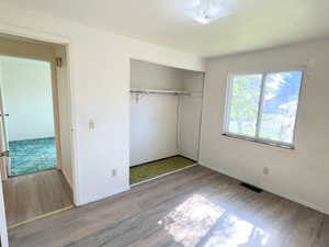 Unfurnished bedroom with a closet and LVP wood-style flooring