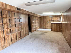 Interior space with carpet flooring, wood walls, and a textured ceiling