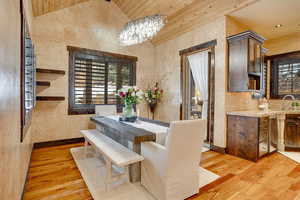 Dining room with baseboards, wood ceiling, vaulted ceiling, wood-type flooring, and a notable chandelier