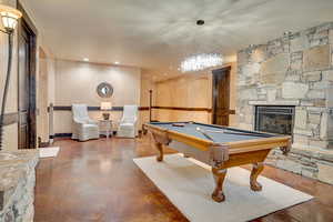 Recreation room with pool table, a stone fireplace, and recessed lighting