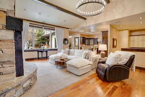 Living area featuring beam ceiling, an inviting chandelier, high vaulted ceiling, and hardwood / wood-style floors