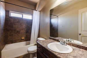 Full bathroom with tile patterned flooring, toilet, shower / bath combination with curtain, and vanity