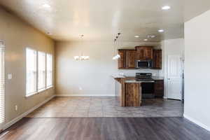 Kitchen with electric range, hardwood / wood-style floors, and decorative light fixtures