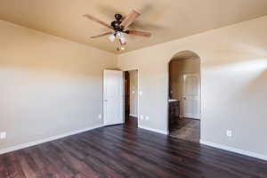 Spare room featuring dark wood-type flooring and ceiling fan