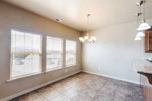 Unfurnished dining area featuring a notable chandelier and light tile patterned flooring