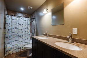 Bathroom featuring dual bowl vanity and toilet