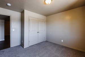 Unfurnished bedroom featuring carpet, a closet, and a textured ceiling