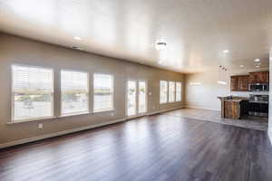 Unfurnished living room with a textured ceiling, sink, a notable chandelier, and wood-type flooring