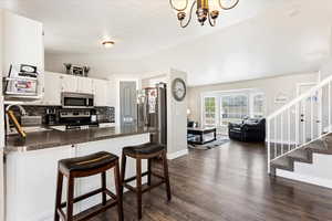 Kitchen featuring stainless steel appliances, sink, lofted ceiling, white cabinetry, and dark hardwood / wood-style flooring