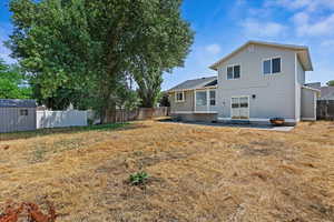 Rear view of property with a shed, a patio, and a yard