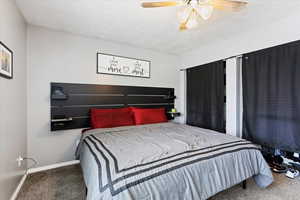 Carpeted bedroom featuring a textured ceiling and ceiling fan