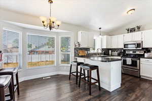 Kitchen featuring appliances with stainless steel finishes, pendant lighting, and dark wood-type flooring