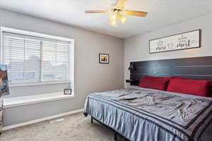 Bedroom featuring a textured ceiling, carpet floors, and ceiling fan