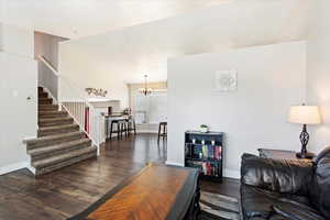 Living room with a notable chandelier and dark hardwood / wood-style flooring