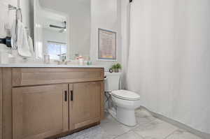 Bathroom featuring vanity, tile patterned floors, ceiling fan, and toilet