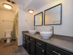 Full bathroom with tile patterned flooring, double sink vanity, toilet, and shower / tub combo with curtain