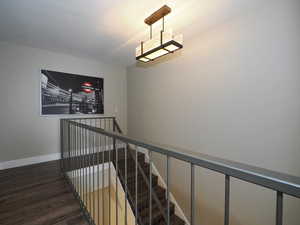 Staircase featuring an inviting chandelier and dark hardwood / wood-style floors