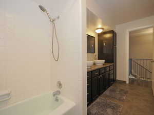 Bathroom featuring tile patterned flooring, double sink vanity, and tiled shower / bath combo