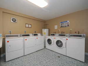 Laundry room with washing machine and clothes dryer, electric water heater, and light tile patterned floors