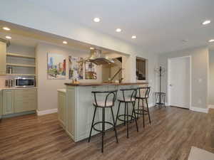 Kitchen featuring dark wood-type flooring, a breakfast bar, and island exhaust hood