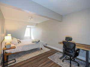 Bedroom featuring baseboard heating and dark hardwood / wood-style flooring