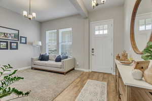 Foyer entrance with a healthy amount of sunlight, a notable chandelier, and light wood-type flooring