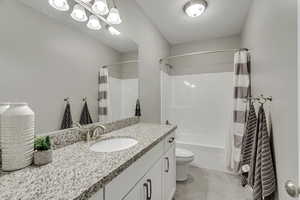 Full bathroom with vanity, shower / tub combo with curtain, toilet, and tile patterned floors