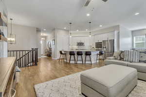 Living room featuring light hardwood / wood-style floors and ceiling fan with notable chandelier