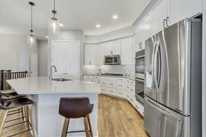 Kitchen featuring tasteful backsplash, light wood-type flooring, a kitchen island with sink, stainless steel appliances, and sink