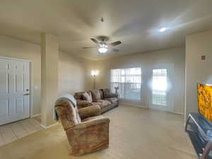 Living area with light carpet, ceiling fan, baseboards, and light tile patterned floors