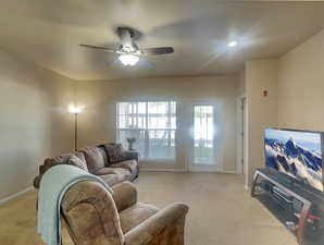 Living room featuring light carpet, a ceiling fan, and baseboards