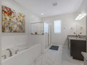 Bathroom featuring tile patterned flooring, shower with separate bathtub, and vanity