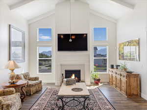 Living room with beam ceiling, dark wood-type flooring, a fireplace, and high vaulted ceiling