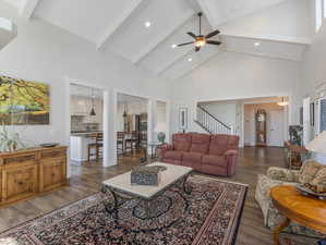 Living room with dark wood-type flooring, high vaulted ceiling, and ceiling fan