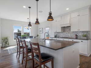 Kitchen with sink, an island with sink, pendant lighting, and dark hardwood / wood-style floors