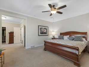 Carpeted bedroom with ornamental molding and ceiling fan