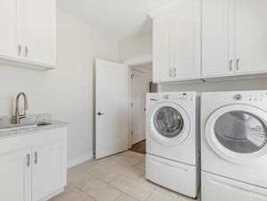 Laundry room featuring sink, independent washer and dryer, cabinets, and light tile patterned floors