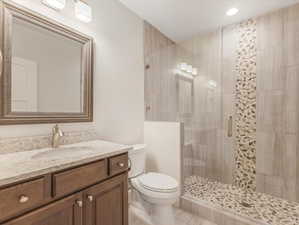 Bathroom featuring tile patterned floors, a shower with door, toilet, and vanity