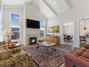 Living room with beamed ceiling, an inviting chandelier, hardwood / wood-style flooring, and high vaulted ceiling