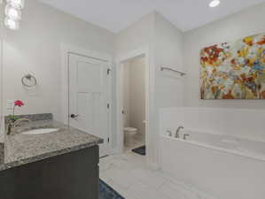 Bathroom featuring vanity, toilet, tile patterned floors, and a bathing tub