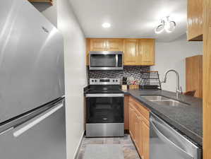 Kitchen featuring appliances with stainless steel finishes, light brown cabinetry, sink, backsplash, and light tile patterned flooring