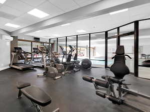 Workout area featuring a wall unit AC, expansive windows, and a paneled ceiling