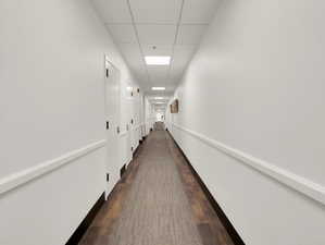 Hallway featuring dark wood-type flooring and a paneled ceiling