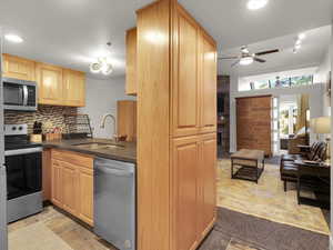 Kitchen with appliances with stainless steel finishes, tasteful backsplash, sink, light tile patterned floors, and ceiling fan