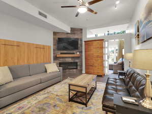 Living room featuring carpet, a tiled fireplace, ceiling fan, and tile walls