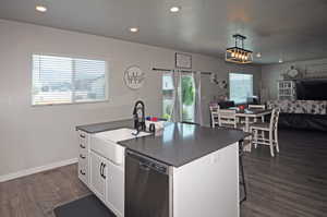 Kitchen featuring a kitchen island with sink, dark hardwood / wood-style floors, dishwasher, and white cabinetry