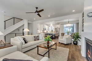 Living room featuring ceiling fan with notable chandelier and wood-type flooring